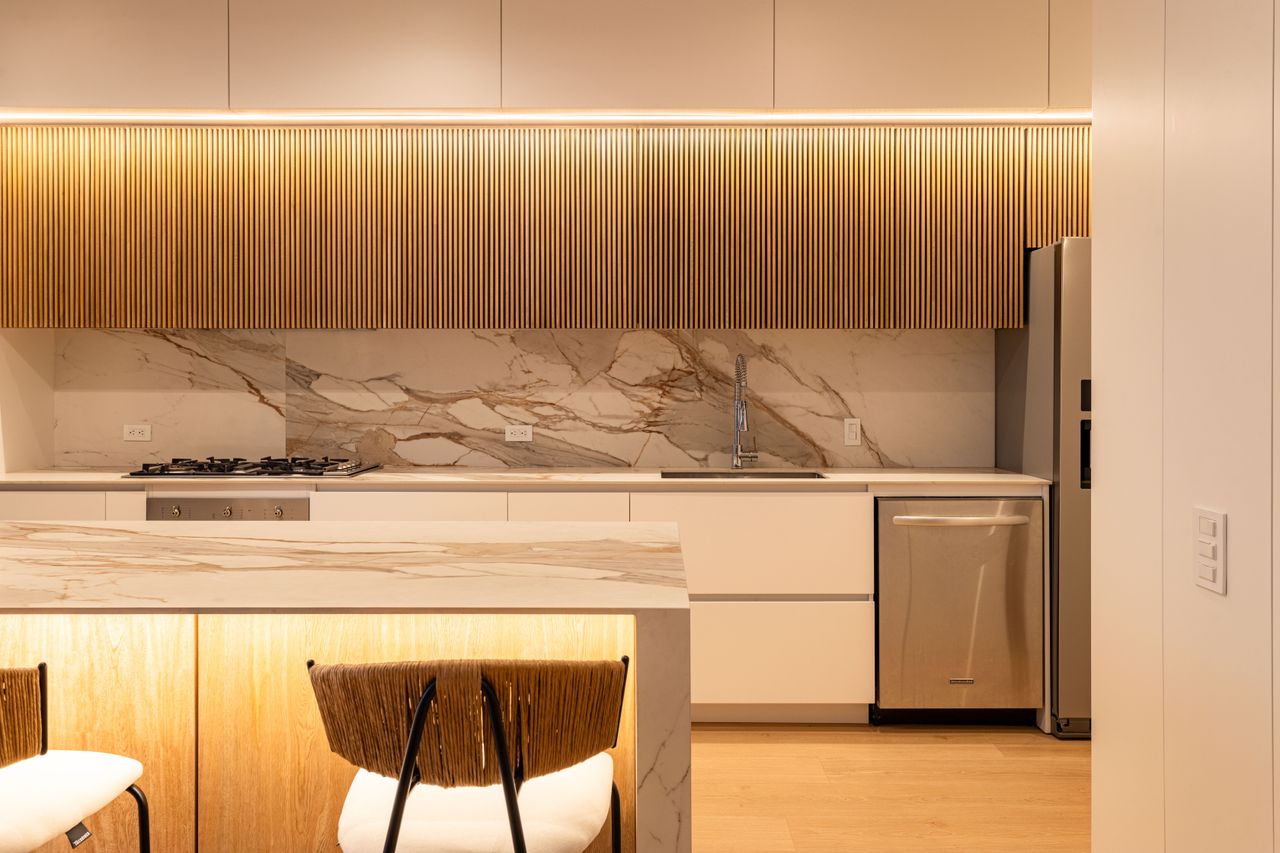 Elegant contemporary kitchen design featuring marble counters and wood panels.